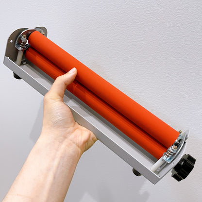 Hand holding a compact A4 cold laminator machine designed for applying cold laminate sheets to sticker paper.