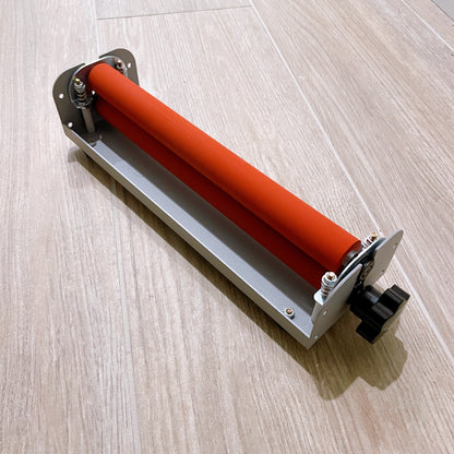 Angled top view of a compact cold laminator machine for A4 paper with orange rollers. This machine is used for applying cold laminate sheets to sticker paper.